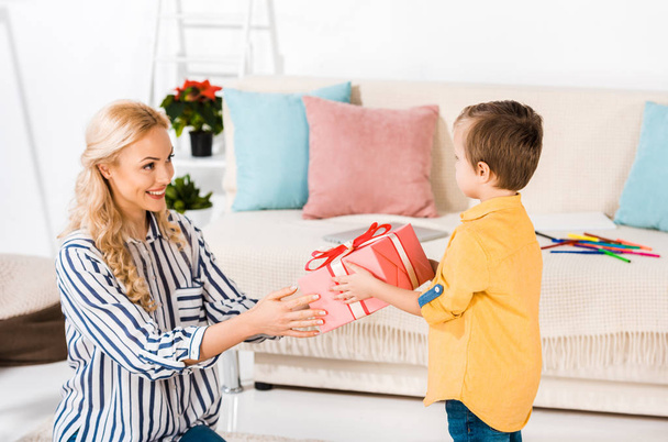 smiling mother presenting gift to little son at home - Photo, Image
