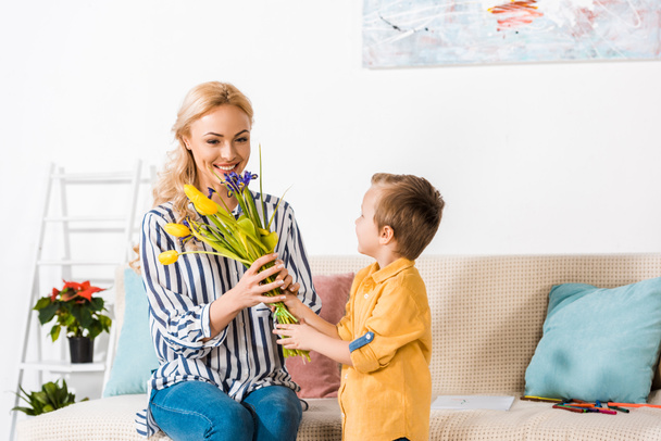 son gifting mother bouquet of flowers on mothers day - Photo, image