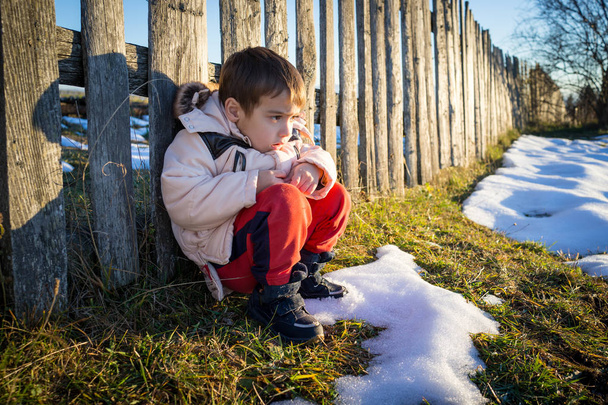 木製のカントリー フェンスの横に雪の中での小さな男の子 - 写真・画像