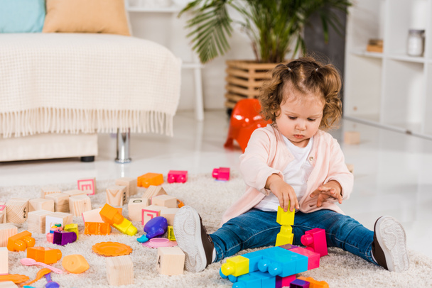 urocze dziecko gra z plastikowych klocków na podłodze  - Zdjęcie, obraz