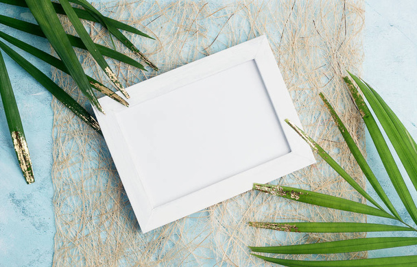 Flat lay horizontal photo frame tropical mock up on craft paper with green and gold palm leaves on blue background. Travel concept. Text space - Fotó, kép