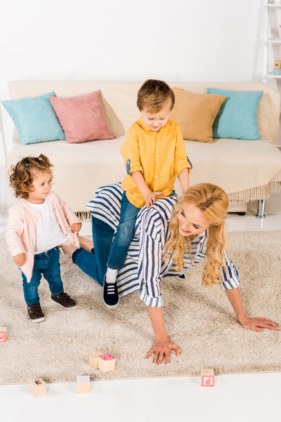 glückliche Mutter spielt mit entzückenden kleinen Kindern zu Hause - Foto, Bild