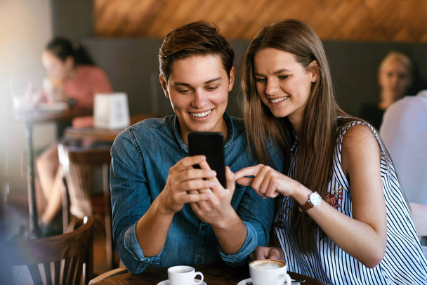 Happy Couple Using Phone, Sitting In Cafe. - Foto, Imagem