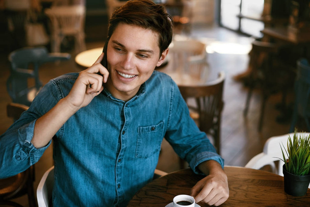 Hombre hablando por teléfono y bebiendo café en el café
. - Foto, Imagen