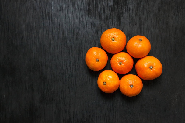 Tangerines on a black background. Lots of fresh fruit - mandarins.  - Φωτογραφία, εικόνα