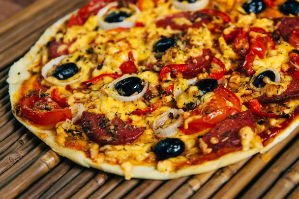 Pizza mit Oliven und Salami auf Bambus-Hintergrund - Foto, Bild