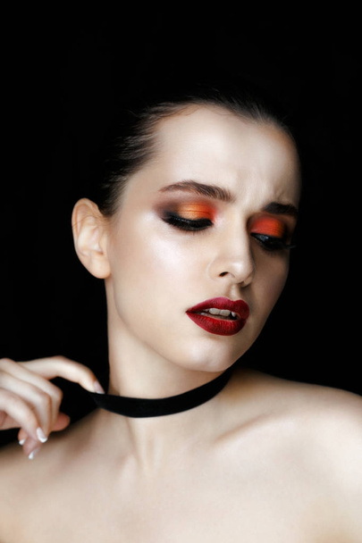 Close-up portrait of gorgeous young woman with fashion make-up against black background  - Fotó, kép
