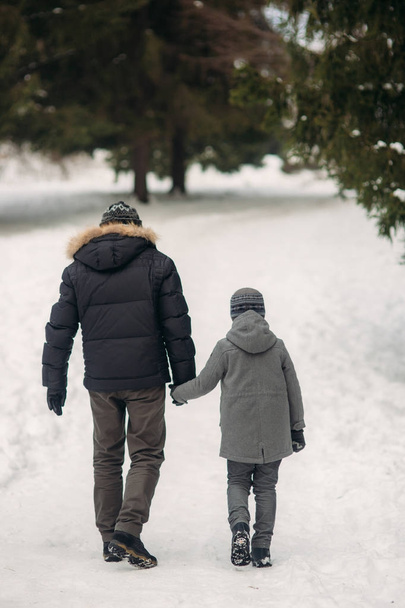 Heureux père avec son fils se promène dans le parc par temps neigeux d'hiver
 - Photo, image
