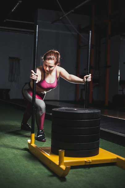 female pushing the prowler exercise equipment on artificial grass turf - Foto, afbeelding