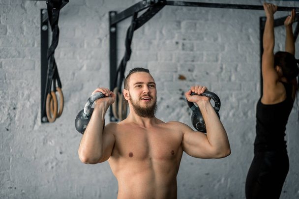 man lifting two kettlebell workout exercise at gym - Foto, immagini