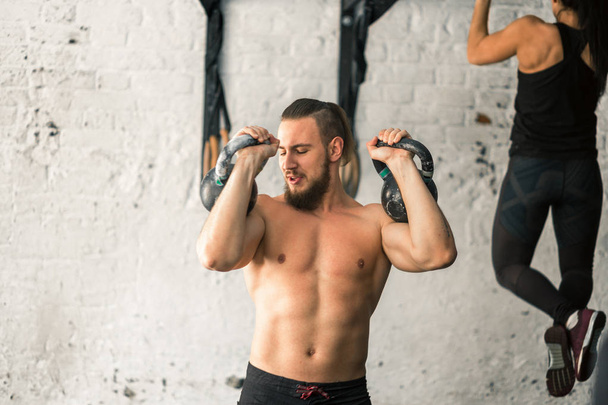man lifting two kettlebell workout exercise at gym - Foto, immagini