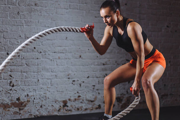 Woman training with battle rope in cross fit gym - Foto, Bild