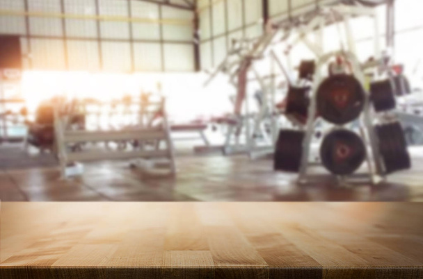 Деревянный стол на размытом фоне фитнес-зала интерьера MO
 - Фото, изображение