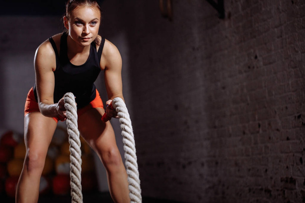 Mujer poderosa hacer ejercicio con cuerdas de batalla en el gimnasio
 - Foto, Imagen