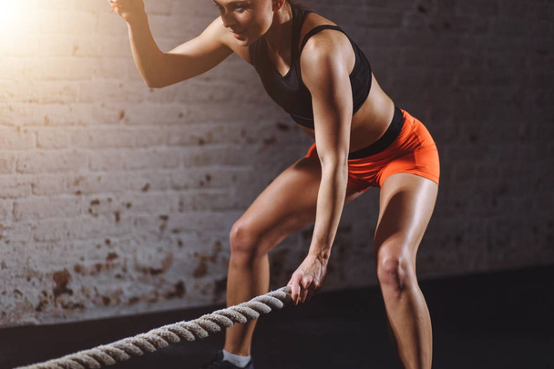 Powerful woman do workout with battle ropes in gym - Foto, imagen