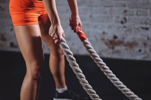 Entrenamiento de mujer con cuerda de batalla en gimnasio cross fit
 - Foto, imagen