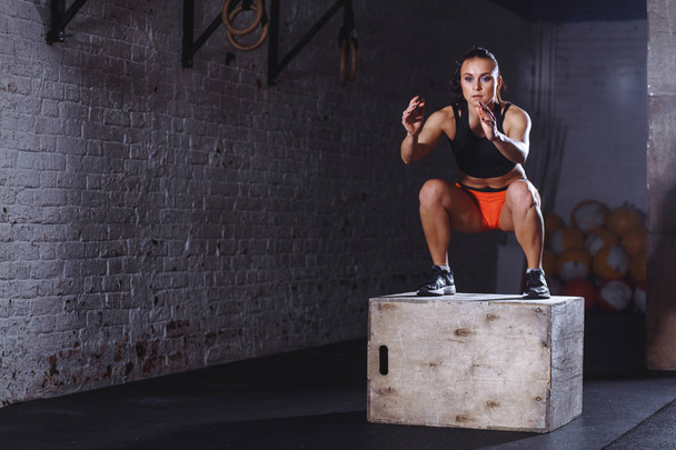 fit woman doing box jump exercise. Muscular woman doing box jumps at gym - Foto, afbeelding