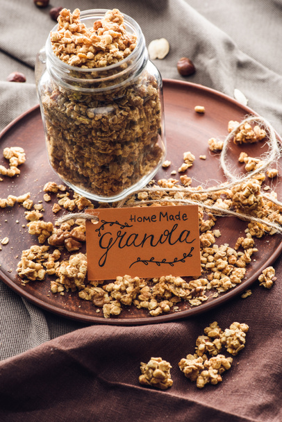 homemade appetizing granola in glass jar with tag on tray - Фото, изображение