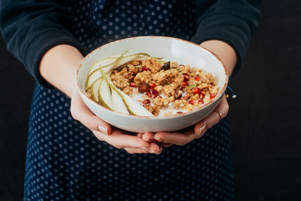 cropped image of female cook holding bowl with granola in hands - Fotoğraf, Görsel