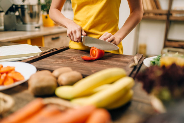 женщина режет овощи на деревянном столе, готовит органические продукты. Вегетарианская диета, здоровый образ жизни
 - Фото, изображение