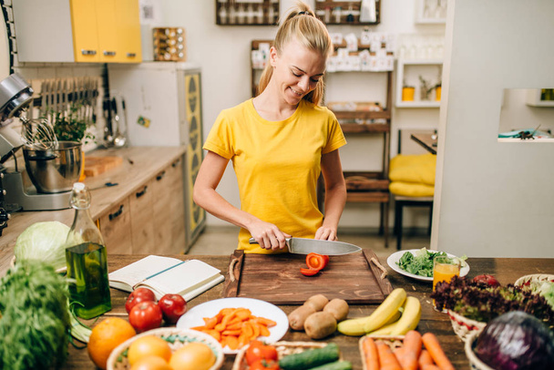 щасливі жінка різання овочі на дерев'яним столом, приготування органічних продуктів харчування. Вегетаріанська дієта, здоровий спосіб життя - Фото, зображення