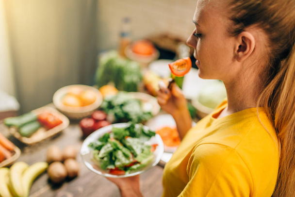 женщина ест салат на кухне, здоровая био-еда приготовления пищи. Вегетарианская диета
 - Фото, изображение