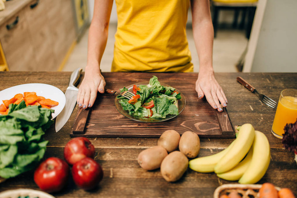 mulher cozinhar salada na cozinha, comida saudável. Dieta vegetariana, legumes frescos e frutas na mesa de madeira
 - Foto, Imagem
