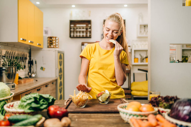 Kobieta jedzenie zdrowe ekologiczne jabłka w kuchni, odmawiają jedzenia śmieciowego jedzenia frytek. Dieta wegetariańska - Zdjęcie, obraz