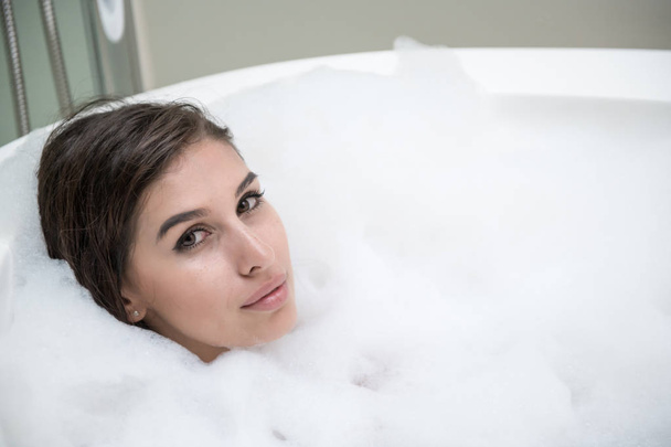 Beautiful young white woman enjoy relaxing in bubble bath. Resting, eye open, smiling. White caucasian woman. - Foto, Imagen