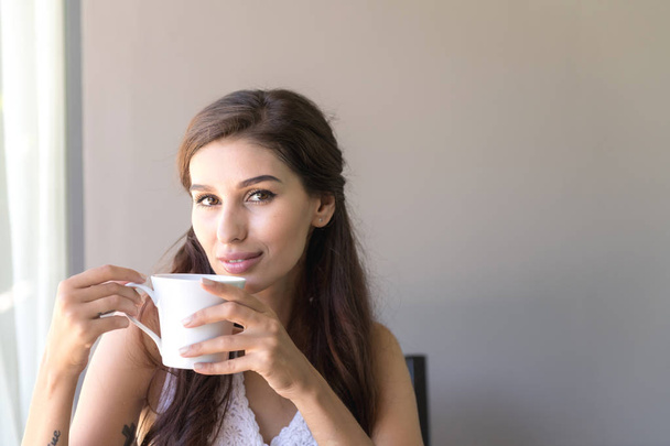 Mujer tomando café y sonriendo. Hermosa mujer blanca tomando su café de la mañana y sonriendo mirando muy feliz
. - Foto, imagen