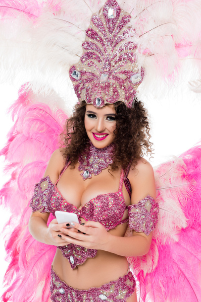 mujer en traje de carnaval usando teléfono inteligente mientras mira a la cámara, aislado en blanco
 - Foto, Imagen