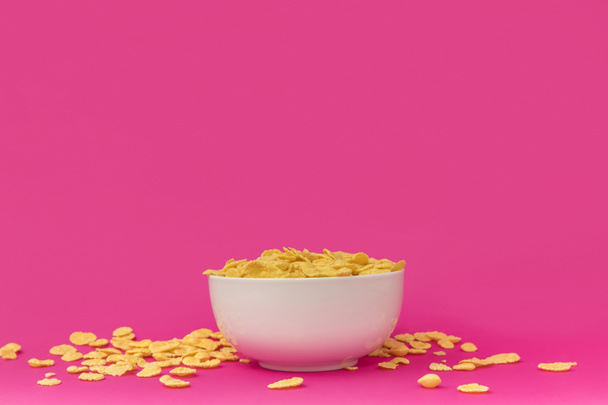 close-up view of white bowl with tasty crunchy corn flakes on pink  - Photo, Image
