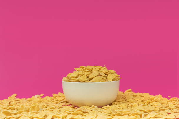 close-up view of white bowl with tasty crispy corn flakes isolated on pink  - Foto, afbeelding