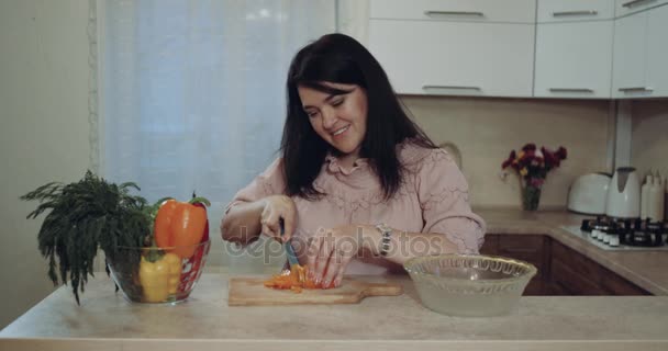 In the kitchen smiling woman cut vegetables. - Imágenes, Vídeo