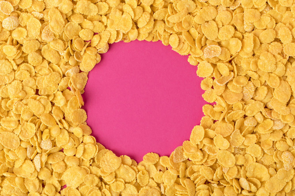верхний вид круга из здоровых органических кукурузных хлопьев на розовый
 - Фото, изображение