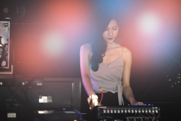 Concept de fête DJ femme. Jeune femme chinoise DJ mixant de la musique sur fond coloré en écoutant sa musique. Mise au point sélective avec fond flou
. - Photo, image