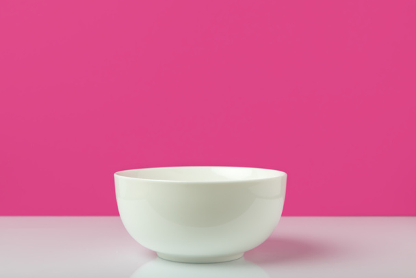 close-up view of single empty white bowl ready for breakfast on pink - Zdjęcie, obraz