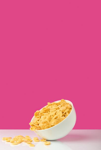 white bowl full of healthy tasty corn flakes on pink   - Foto, afbeelding