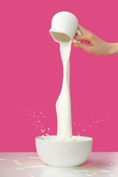 partial view of person pouring fresh healthy milk from jug to bowl on pink   - Photo, Image