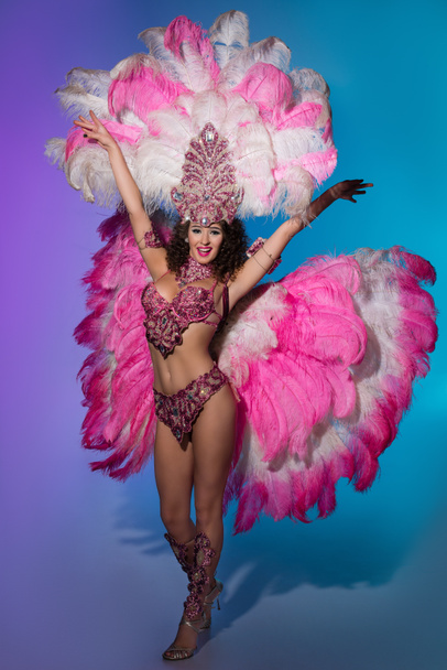 Bright woman in carnival costume with pink feathers on blue background - Фото, изображение