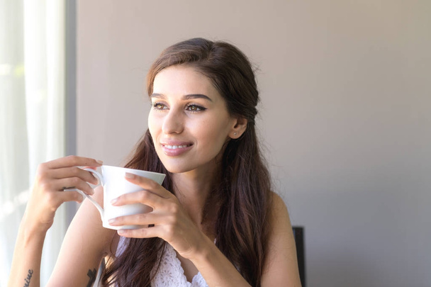 Nainen kahvilla ja hymyilee. Kaunis valkoinen nainen ottaa hänen aamulla kahvia ja hymy näyttää erittäin onnelliselta
. - Valokuva, kuva