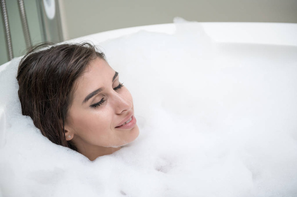 Beautiful young white woman enjoy relaxing in bubble bath. Resting, eye close. White caucasian woman. - Фото, зображення
