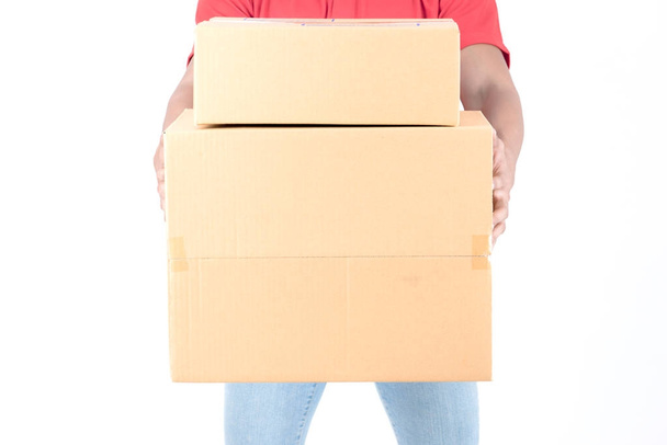 Young logistic career concept. Happy delivery man with box. Isolated on white background. Asian chinese fit man in red polo shirt and jeans with red hat in his early twenties. - Zdjęcie, obraz