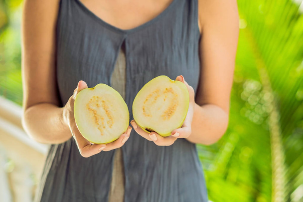 guava in beautiful female hands on a green background.. - Fotografie, Obrázek
