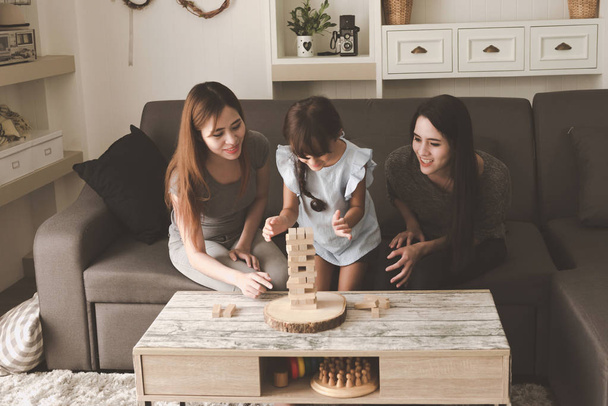 Two woman playing puzzle game with their daughter in living room. Family fun time concept. - Valokuva, kuva