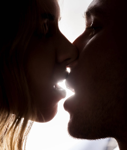 Close-up of young couple in passionately kissing on bright background - Photo, Image