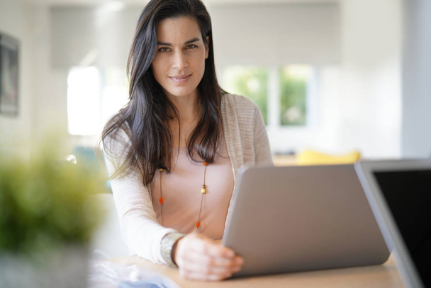 Portrait of brunette girl working on laptop computer - Фото, зображення