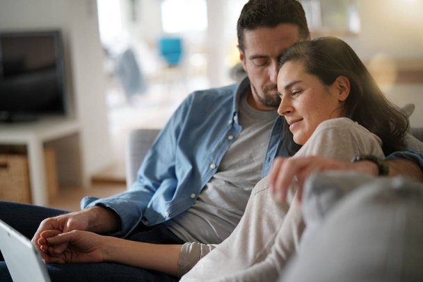 Ζευγάρι, χαλαρώνοντας στον καναπέ και να συνδεθεί με ψηφιακές tablet - Φωτογραφία, εικόνα