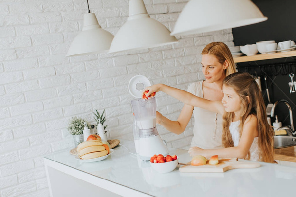 Mother and daughter preparing shealthy smoothie - Photo, image