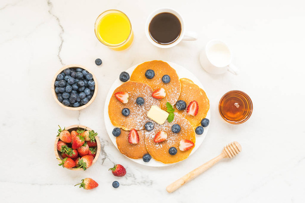 Zdrowe śniadanie zestaw z naleśnik owoce jagód i truskawek i czarnej kawy, mleka i soku pomarańczowego na tle biały kamienny stół - Zdjęcie, obraz